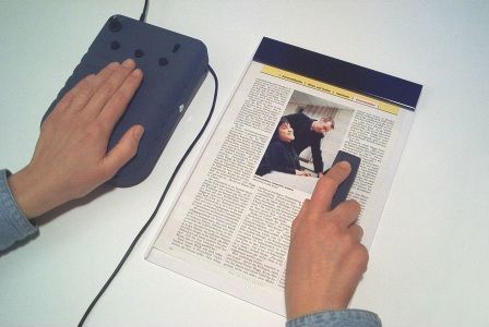 Bild: Eine Hand liegt auf dem VideoTIM1, die andere fhrt die kleine Hand-Videokamera